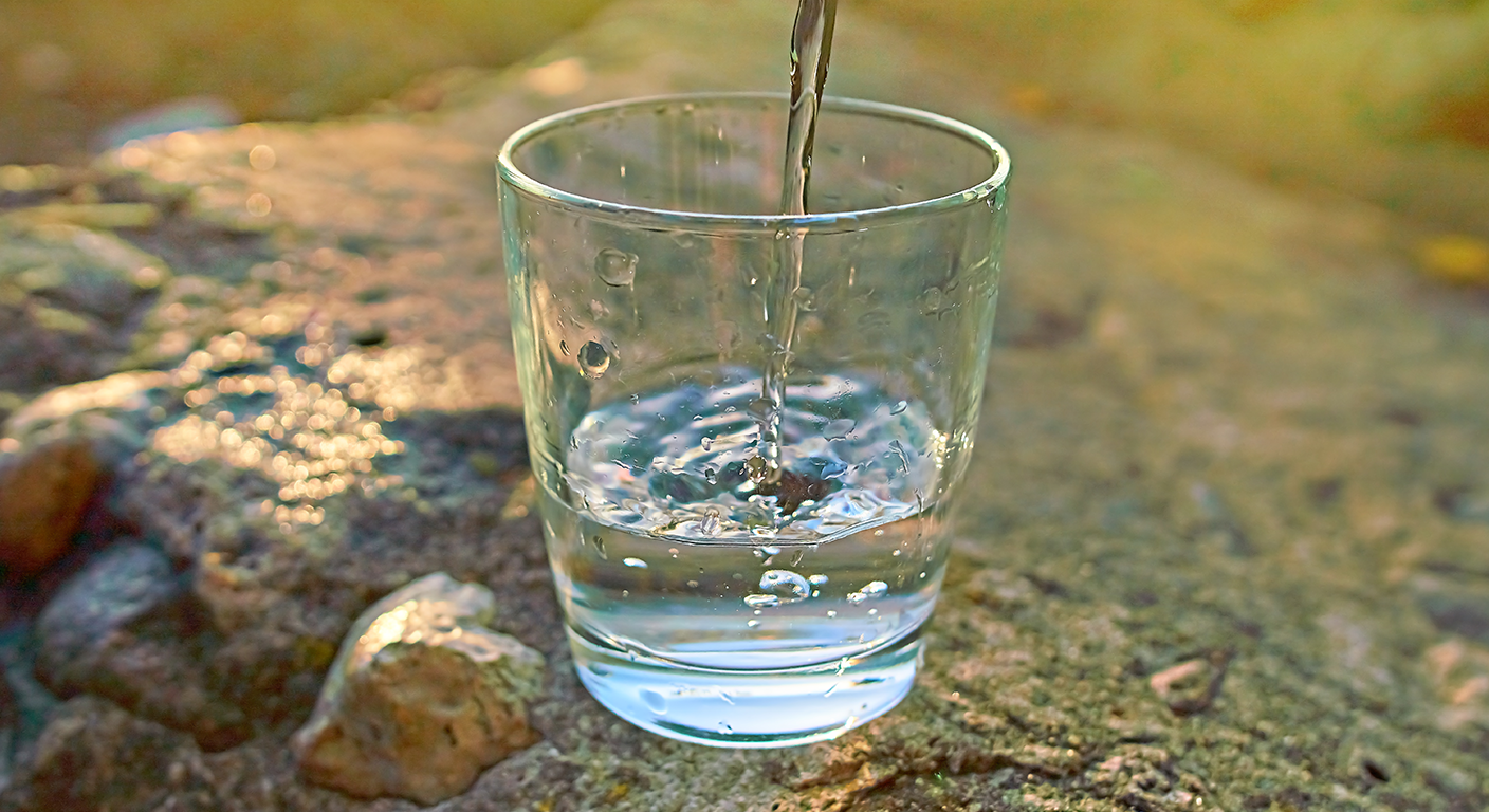 Water being poured into a clear glass outdoors